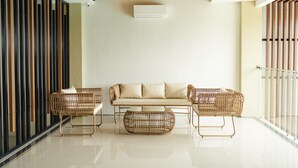 Un interior moderno con un sofá, dos sillones de mimbre y una mesa de centro redonda.