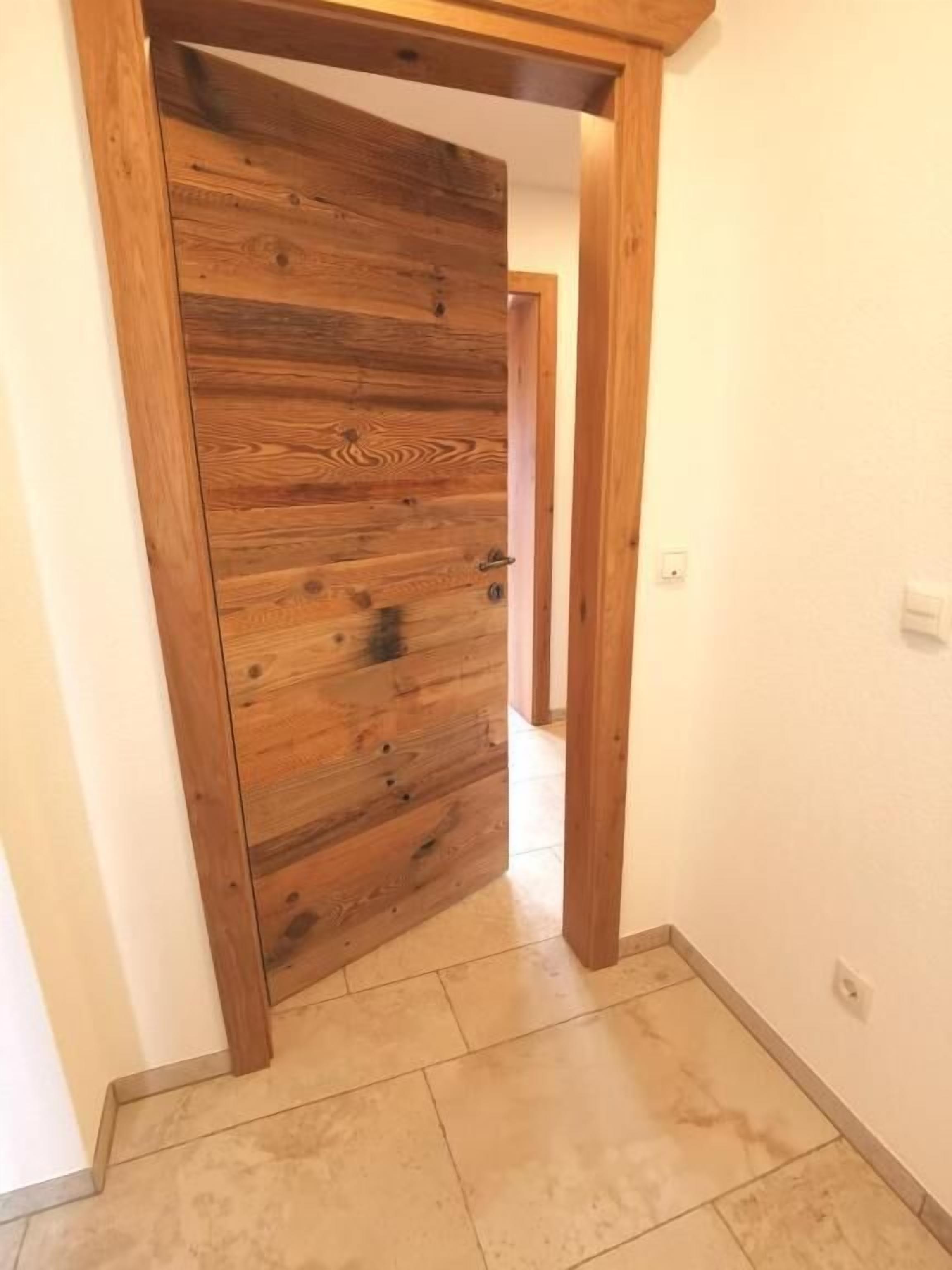 A hallway with a wooden door and a tiled floor.