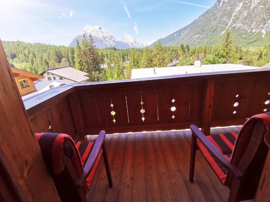 Terraza de madera con dos sillas y vista a un paisaje montañoso.