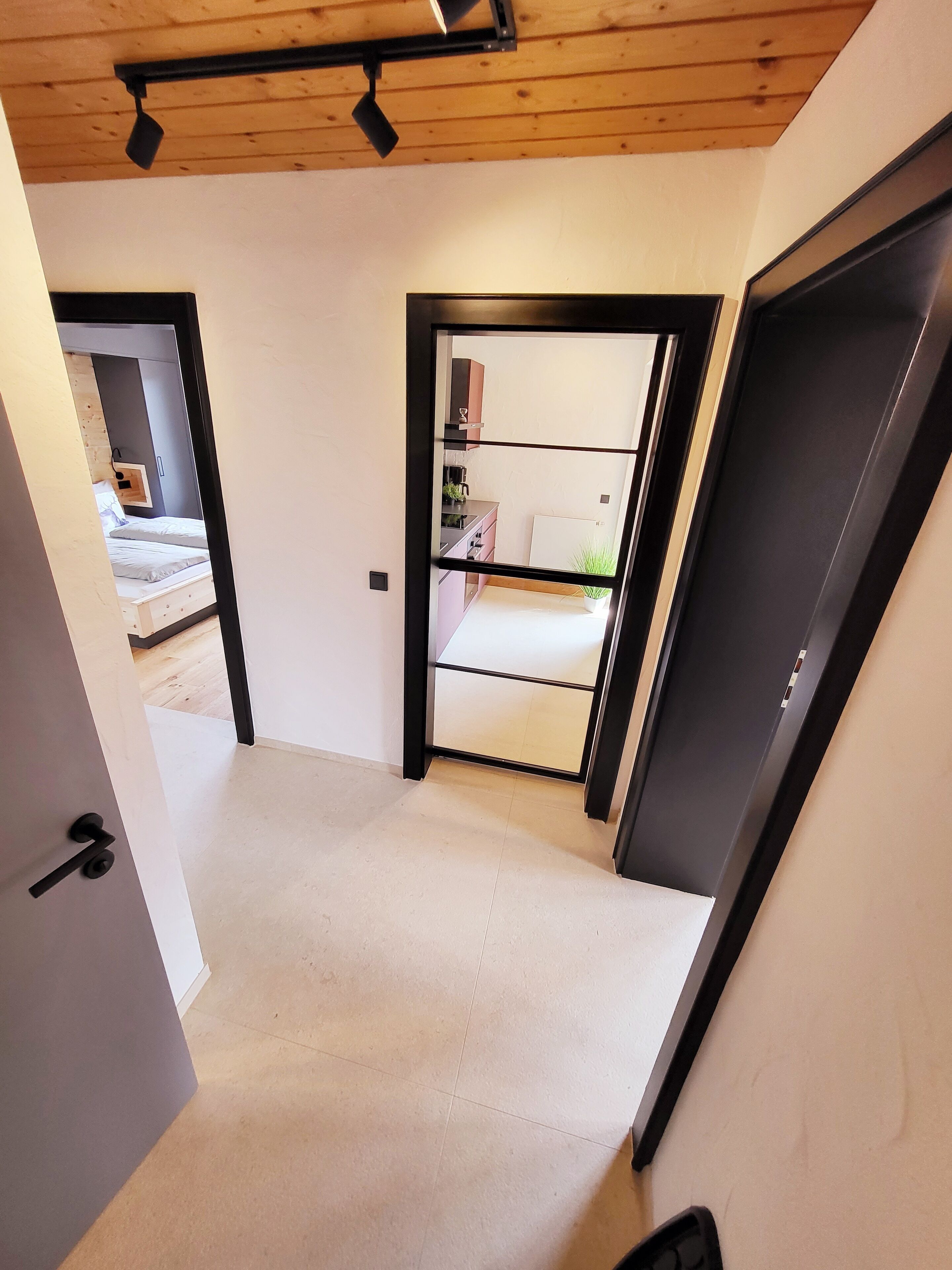A modern interior with a visible bedroom, kitchenette, and a door leading to another room.