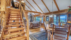 A wooden interior with a staircase, a dining area with a rug, and a view through large windows. - Blue Ridge Tradition -View, location, dog friendly (Blue Ridge)