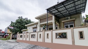 Ein zweistöckiges Haus mit geschlossenem Eingangstor, einer Veranda und einem kleinen Balkon.