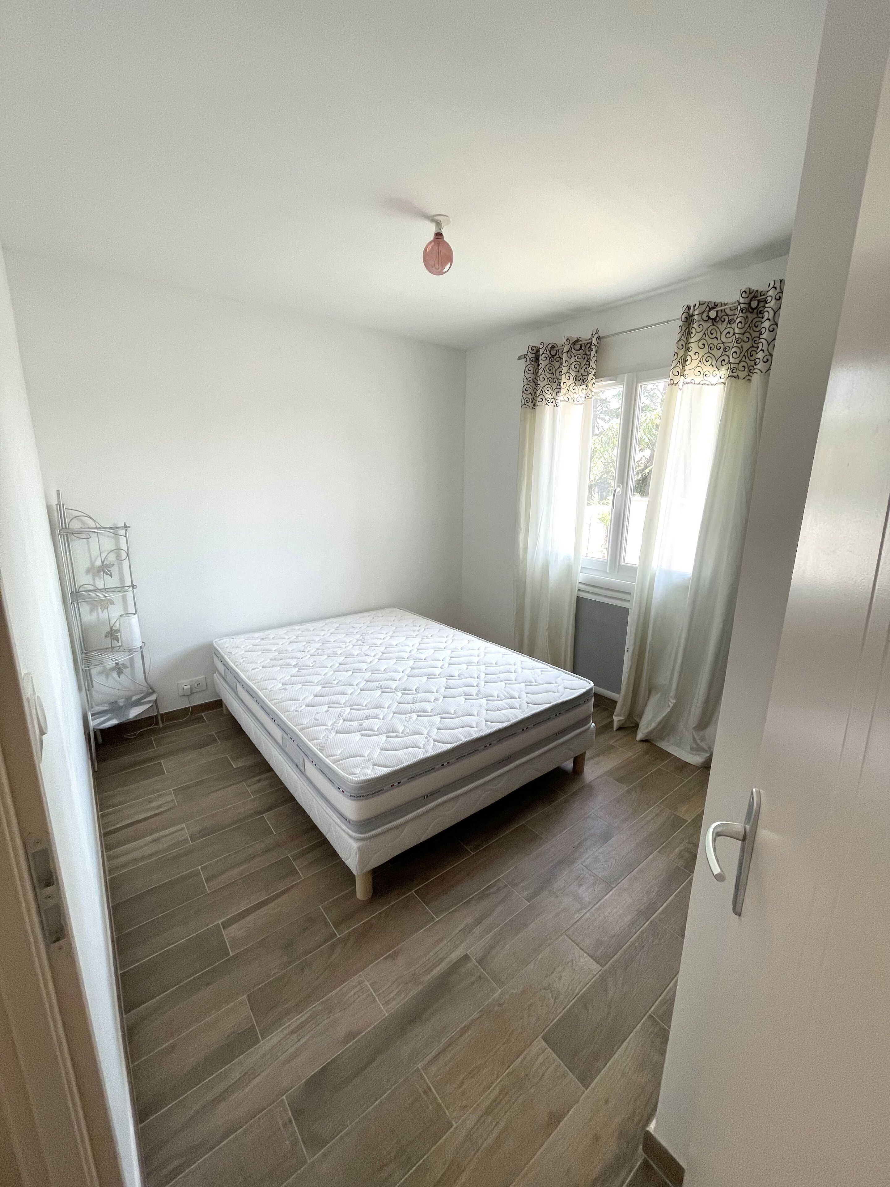 Un dormitorio con una cama individual, un radiador, una ventana con cortinas y una puerta.