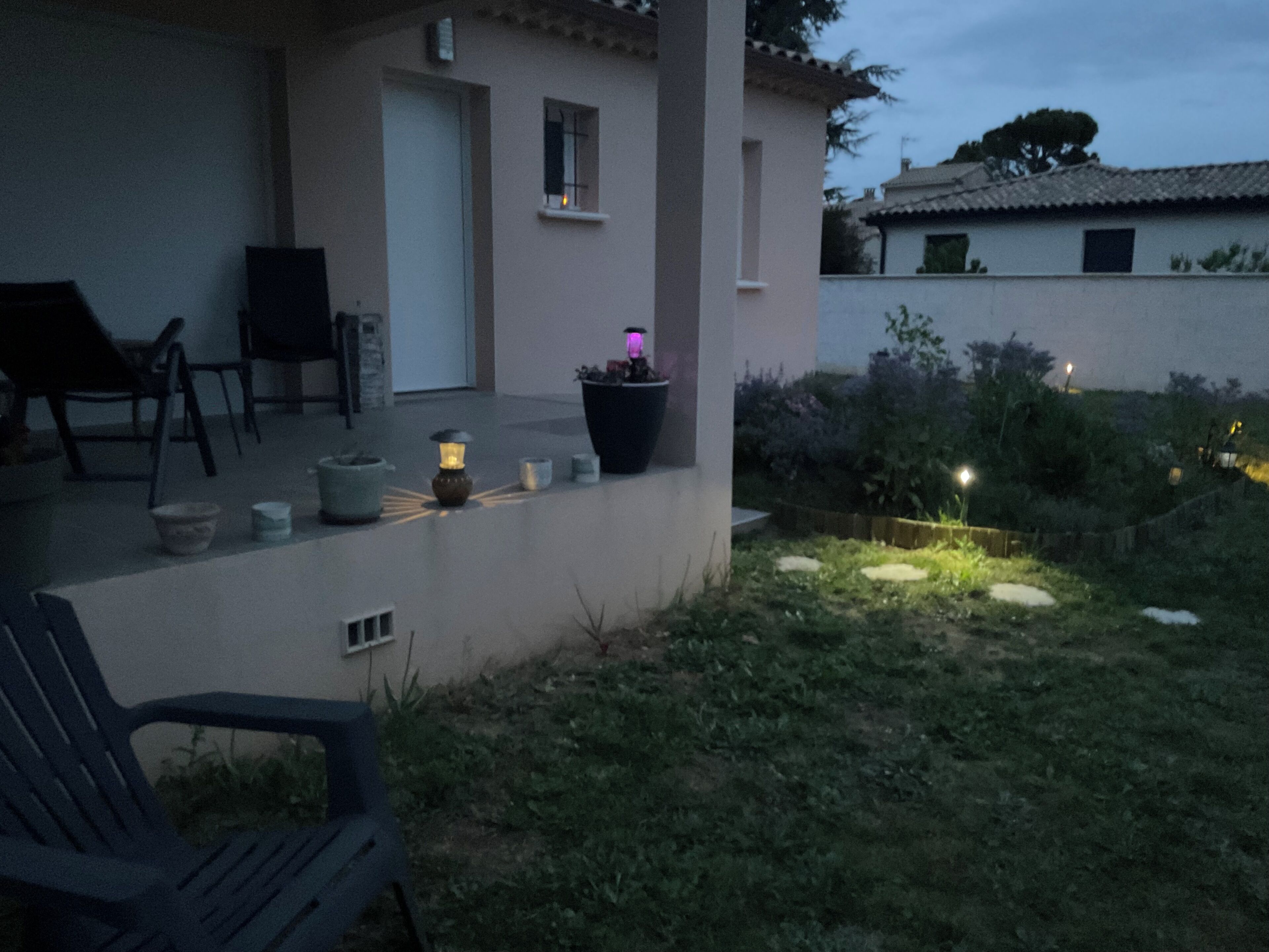 Een terras met buitenmeubilair, een bloempot en een kleine tuin.