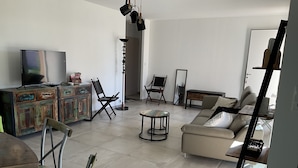 A spacious living room with a sofa, chairs, a coffee table, and a television.