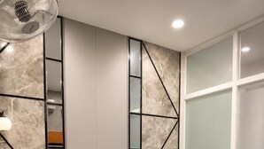 Une chambre d’hôtel avec un lit en bois, du linge de lit blanc, un petit bureau avec une lampe et un miroir.
