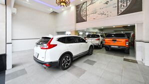Un centre de lavage automobile à plusieurs niveaux, avec plusieurs véhicules, dont un VUS blanc et un camionnette orange, ainsi qu’un mur décoratif orné d’une fresque représentant un arbre et des oiseaux.