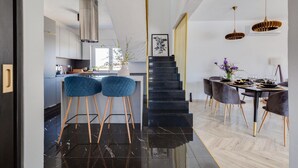 Una cocina moderna con una escalera negra que lleva a un comedor.