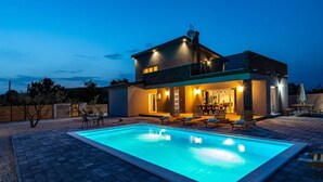 Una casa moderna de dos pisos con piscina, mobiliario exterior y antena parabólica.
