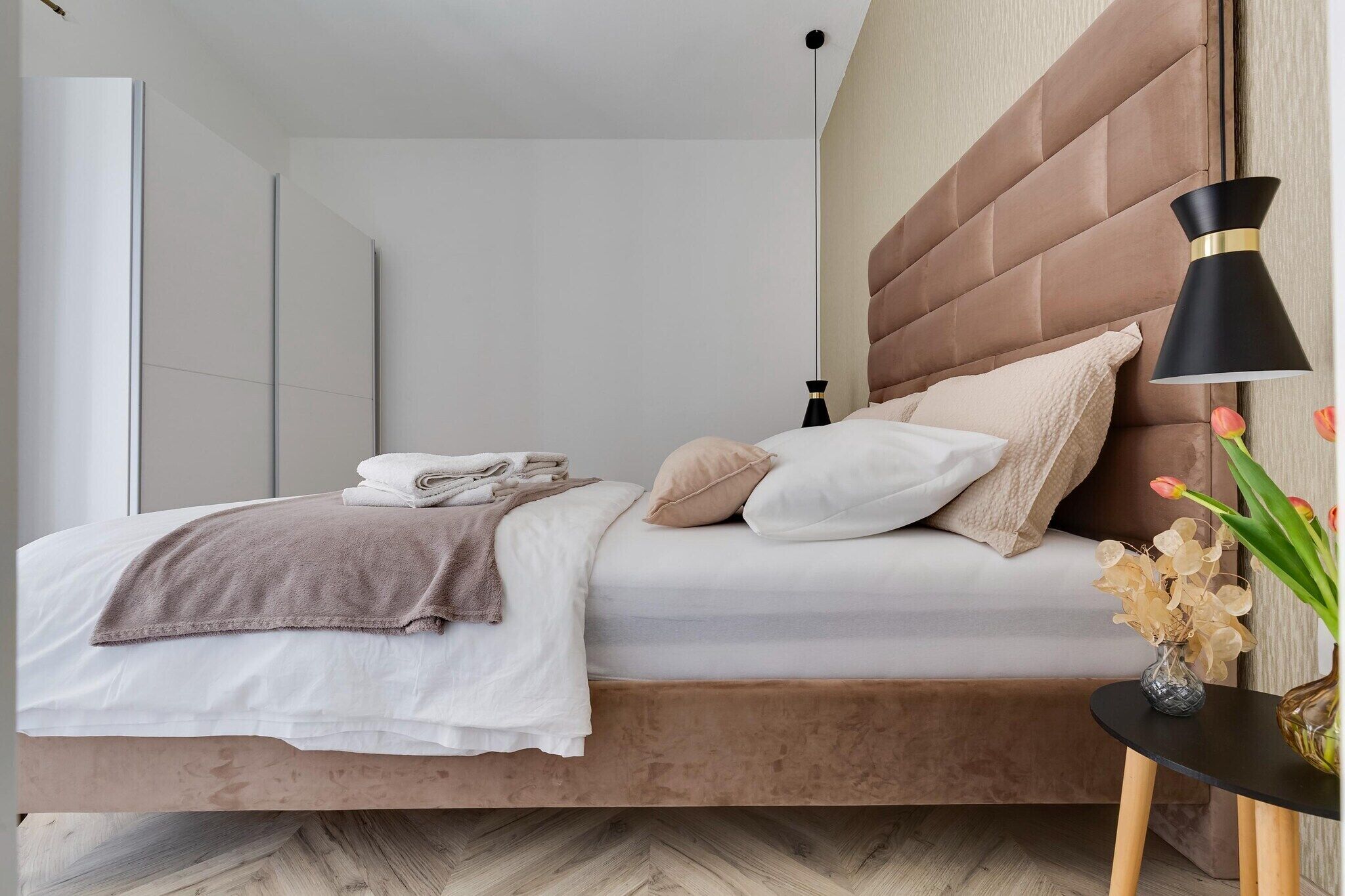 A modern bedroom with a bed, bedside table, and a lamp.