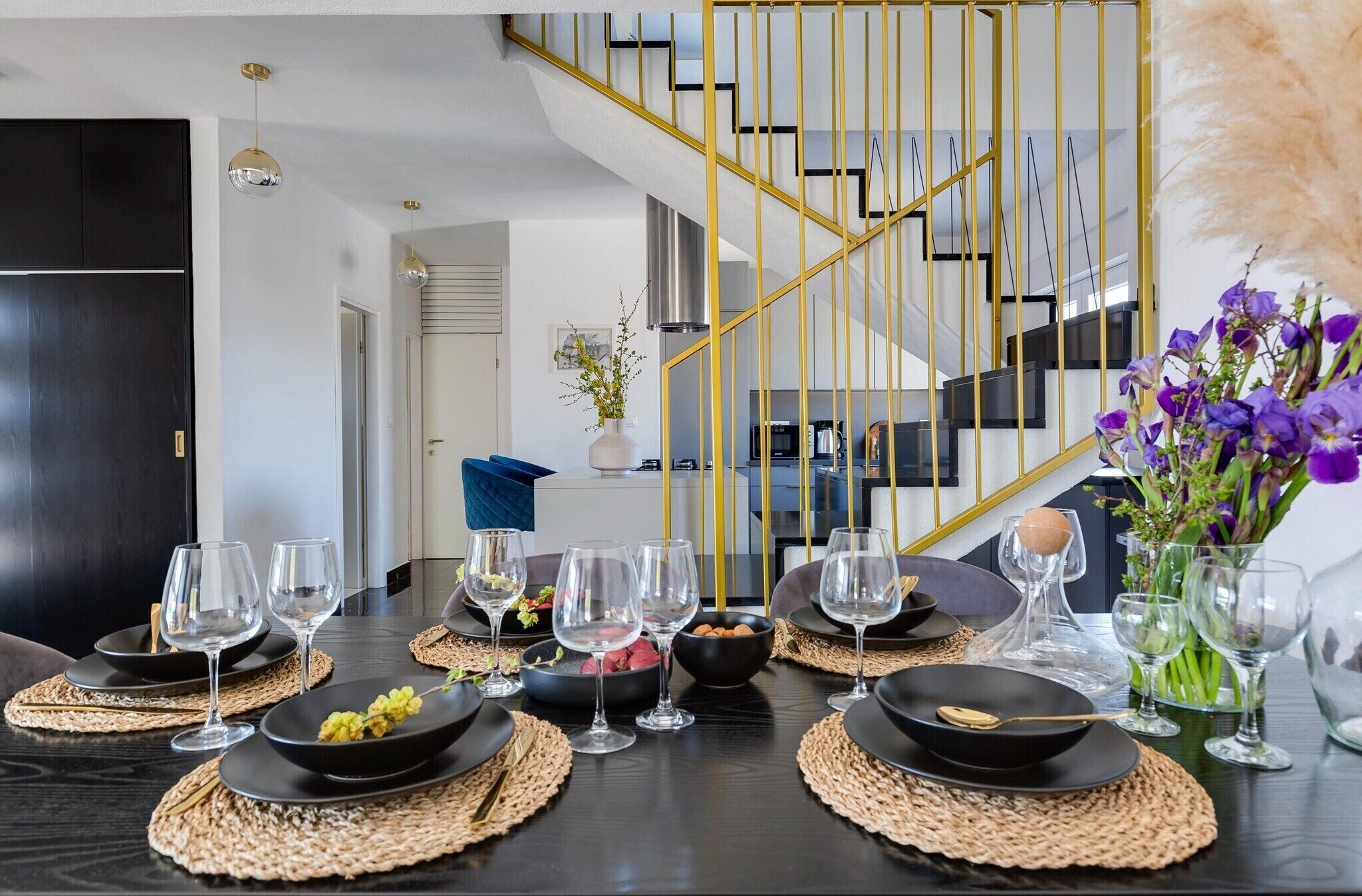 Un espace repas doté d’un escalier moderne, de tables de salle à manger noires et de verres transparents.