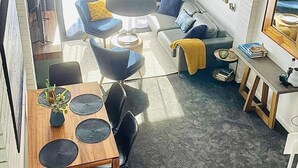 A modern living room with a sofa, chairs, a dining table, and a large window.