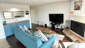 A living room with a blue sofa, a coffee table, a TV, and a fireplace. - 2BDR/2.5BTH, located less than 2 miles from Canyon Lake. Hot-tub, stunning views, nearby golf course (Canyon Lake)