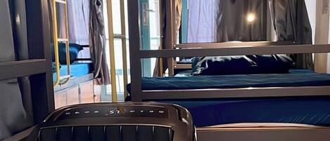 A compact room with a bed, a white Philips air purifier, and a wooden floor.