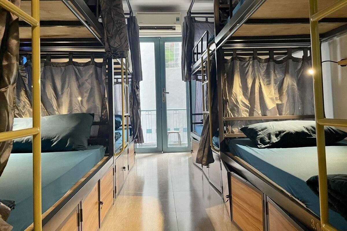 A narrow corridor with bunk beds on either side, leading to a door with a view of a balcony.