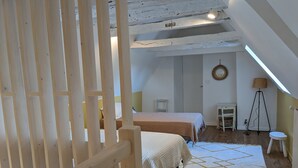A cozy attic bedroom with two beds, a small table, a floor lamp, and a view of the outside. - Romantic french cottage 6 persons with pool, 15 min from Rocamadour/Dordogne (Reilhaguet)