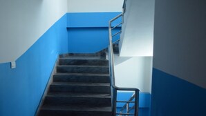 Una escalera con paredes azules y barandilla de metal.