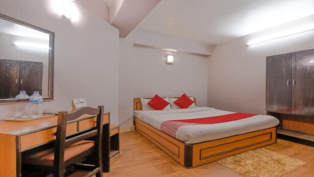 Un dormitorio con cama, escritorio, silla, armario y espejo.