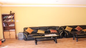 Una sala de estar con un sofá de cuero negro, dos mesas de centro, una estantería y un aparador.