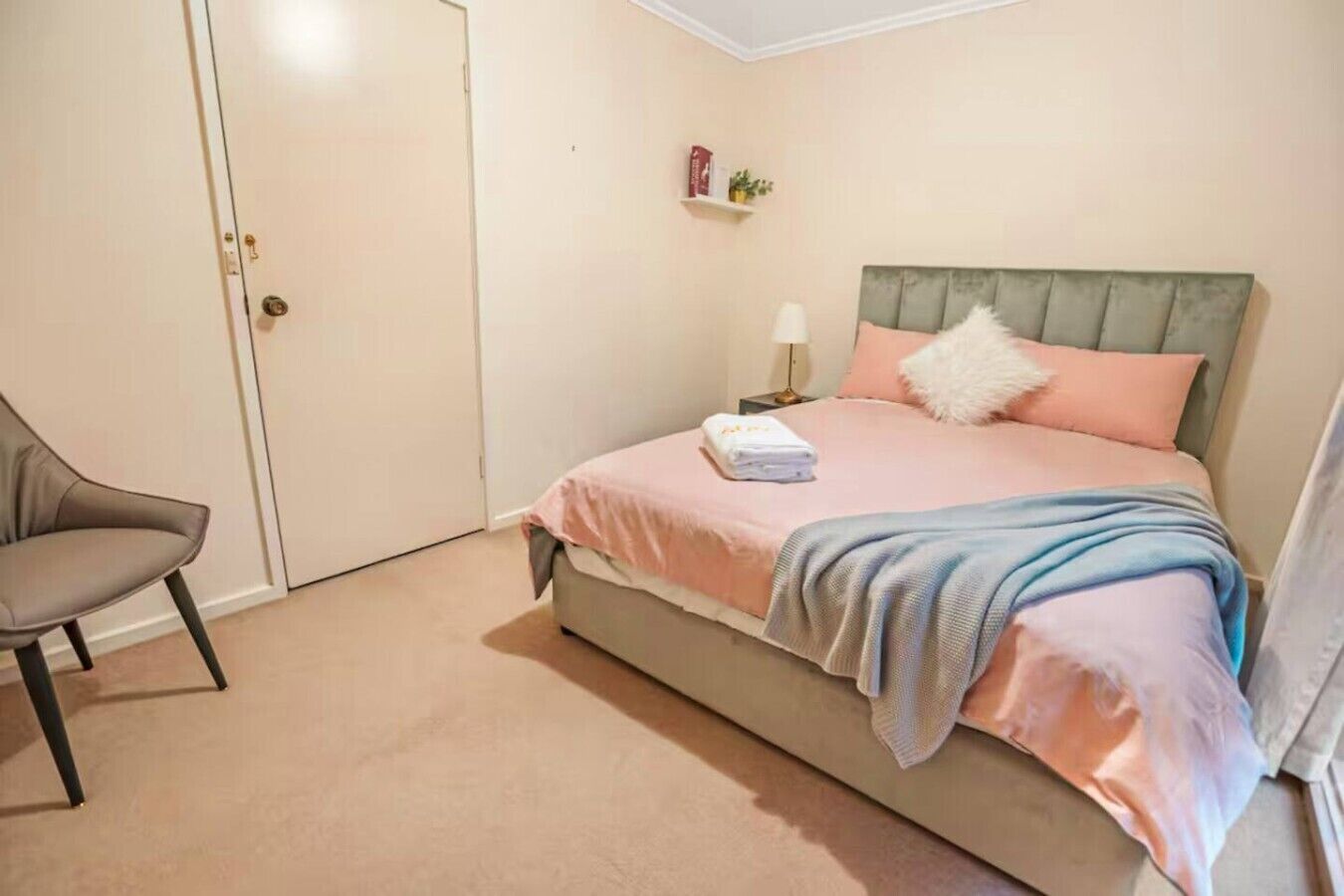 Une chambre à coucher avec un lit, une chaise, une table de chevet et une porte.
