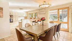 Una cocina amplia con armarios blancos, una mesa de comedor con sillas y un candelabro.