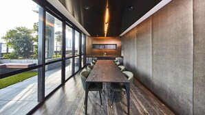 Uma sala de conferência com uma mesa comprida, cadeiras e vista através de grandes janelas.