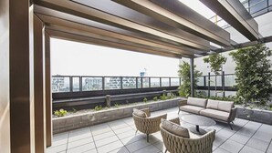 Terraço no telhado com um sofá, cadeiras e uma mesa.