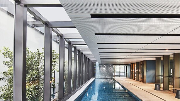 Piscina interior moderna com paredes de vidro e um longo corredor.