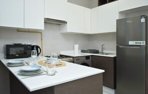 A modern kitchen with a microwave, kettle, and refrigerator.