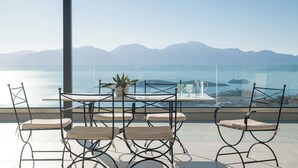 Una terrazza con tavolo e sedie, una pianta in vaso e vista sul mare e sulle montagne.