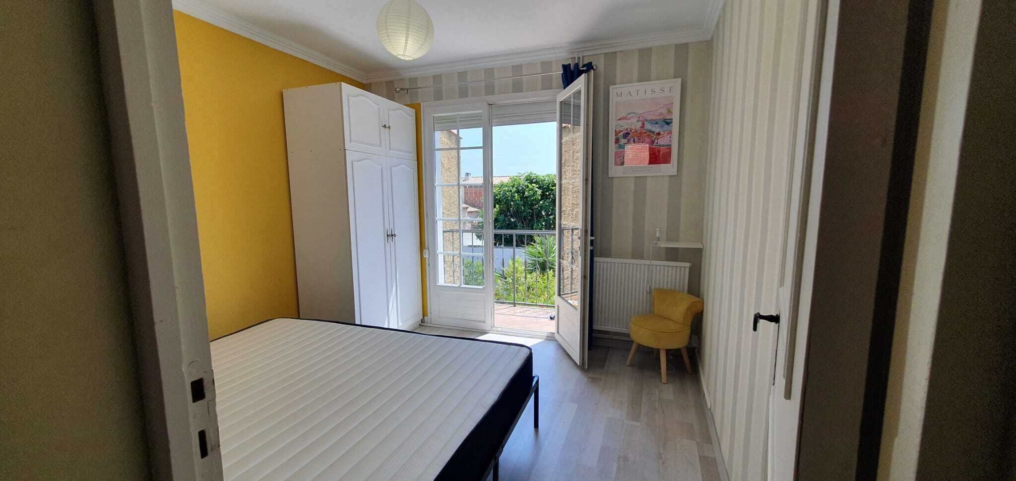 Ein Zimmer mit einem Bett, einem Kleiderschrank, einem Stuhl und einer Tür zu einem Außenbereich.