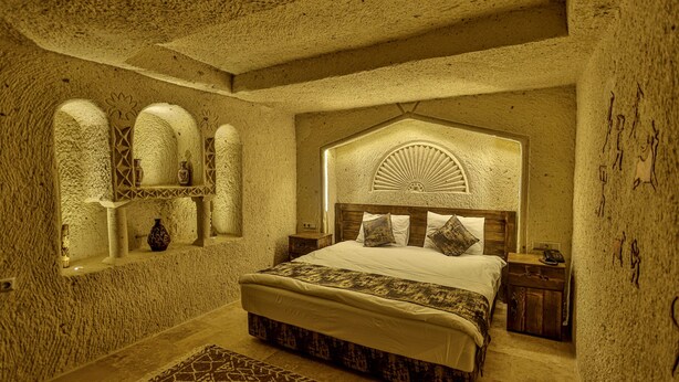 Una camera da letto con un letto grande, una testiera in legno e un soffitto decorato.