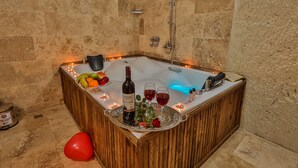 Una vasca da bagno in legno con un vassoio che contiene una bottiglia di vino, due bicchieri di vino rosso e una rosa.
