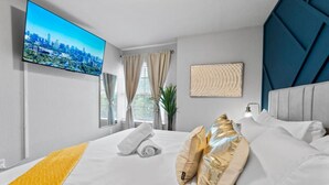Ein modernes Hotelzimmer mit einem großen Bett, einem Flachbildfernseher, Blick auf die Stadt und einer Pflanze.