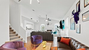 Ein modernes Wohnzimmer mit einer Couch, Sesseln, einem Couchtisch und einer Treppe.