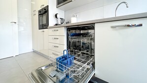 Una cocina moderna con armarios blancos, horno empotrado, microondas y lavavajillas.