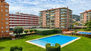 Complejo residencial con múltiples balcones, piscina y césped bien cuidado.
