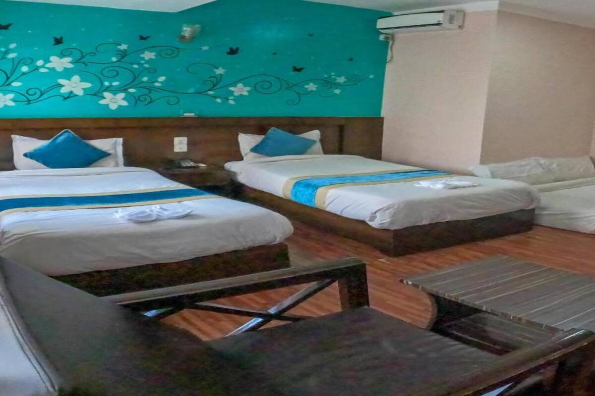 Habitación de hotel con dos camas, una mesa de madera y un adorno en la pared.