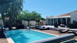 A modern outdoor pool area with a clear blue pool, lounge chairs, and a small playhouse. - Grande Villa Avec Piscine Proche mer + Bateau (Mireval)
