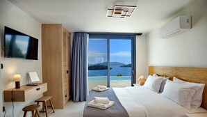 Een moderne hotelkamer met een groot bed, een bureau met stoel, een flatscreen televisie en uitzicht op zee.