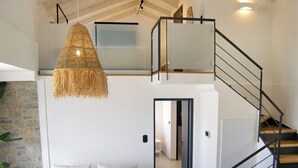 Een modern interieur met een witte bank, een hanglamp en een trap.