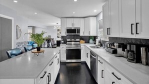 A modern kitchen with white cabinets, stainless steel appliances, and a central island with seating. - 6BR | Fire Pit, Games, Theater Room + EV Charger (Long Pond)