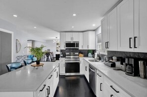 A modern kitchen with white cabinets, stainless steel appliances, and a central island with seating.