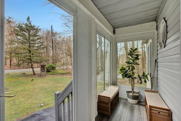 Relax on the covered porch with a view of the lush yard and trees.