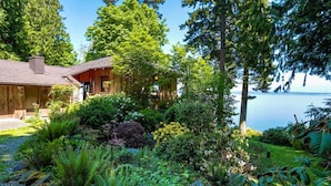 A wooden cabin with a garden and a view of the water. - Family Friendly Water View Retreat w/ Sauna (Port Ludlow)
