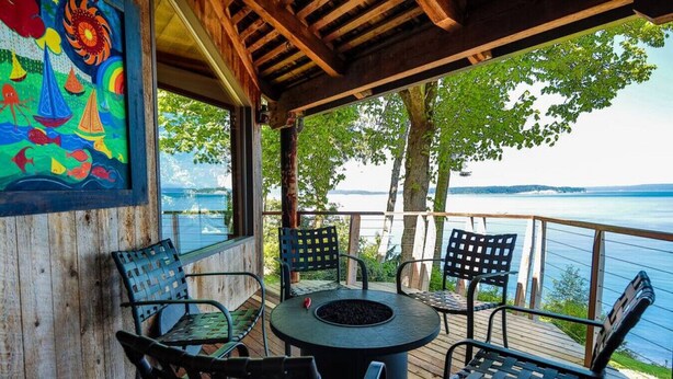 A covered outdoor seating area with a table and chairs, overlooking a body of water. - Family Friendly Water View Retreat w/ Sauna (Port Ludlow)