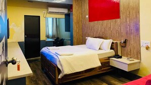 Habitación de hotel con cama, mesita de noche y ventilador de techo.