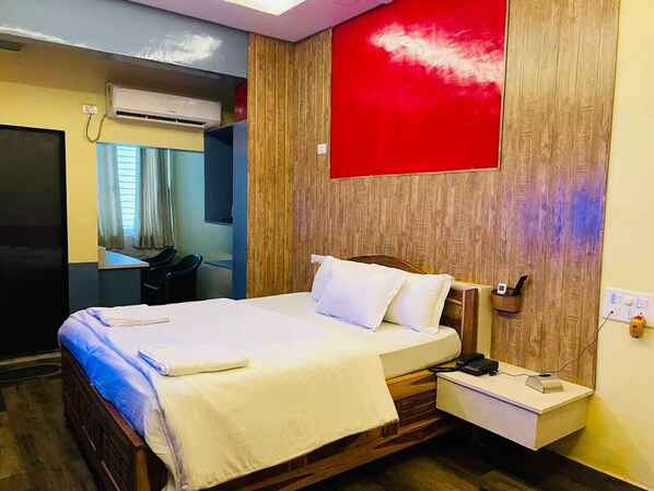A hotel room with a bed, bedside table, and a red accent wall. - Wayfare SP Resort (Panvel)