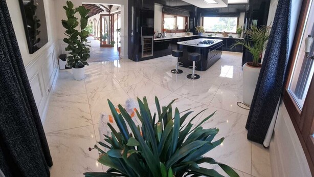 Una cocina moderna con una isla central, muebles negros y un amplio ventanal que proporciona luz natural.