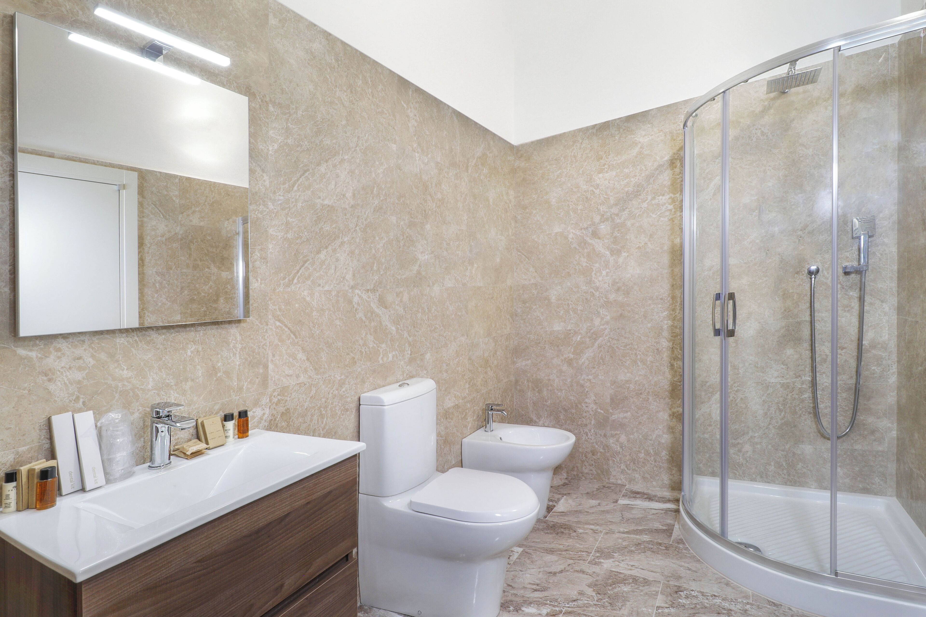 A modern bathroom with a white sink, a toilet, and a glass-enclosed shower.